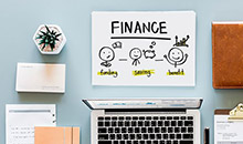 A desk with a laptop and sign saying Finance