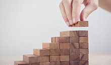 A person creating a mini staircase with toy wooden blocks