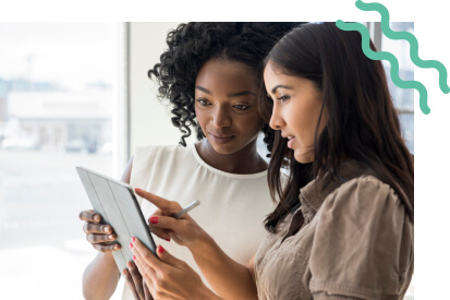 Two women talking holding an iPad and pointing at the screen.