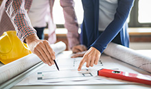 Two people pointing at blueprints deciding a layout for restaurant.