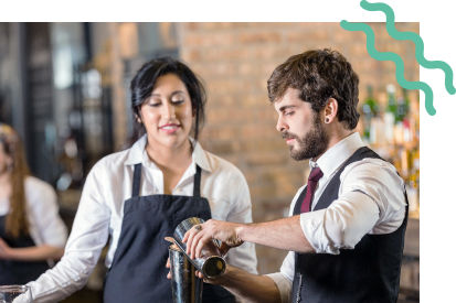 Two restaurant workers, one worker pouring a drink.