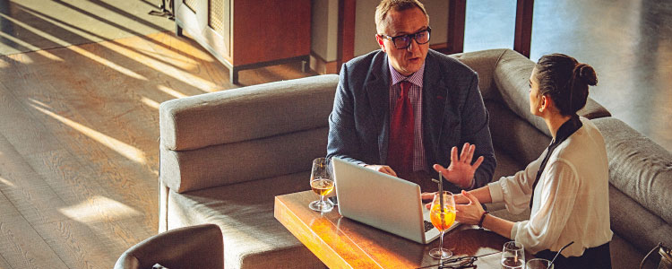 Two people talking with the laptop in front of them.